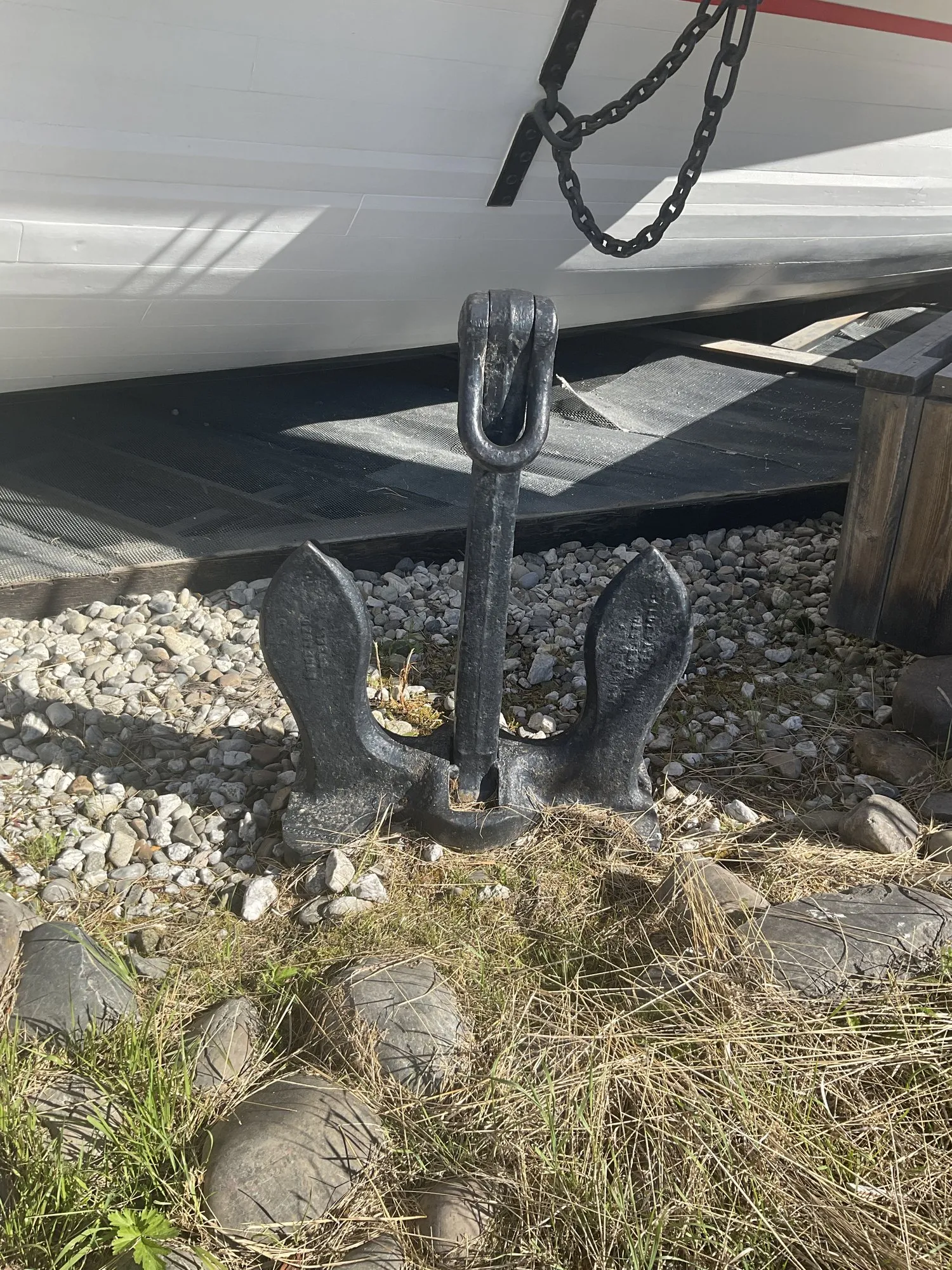 Black stockless anchor resting on gravel beneath the hull
